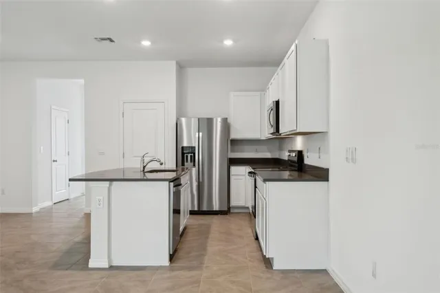 a kitchen with stainless steel appliances granite countertop a refrigerator a stove and a sink