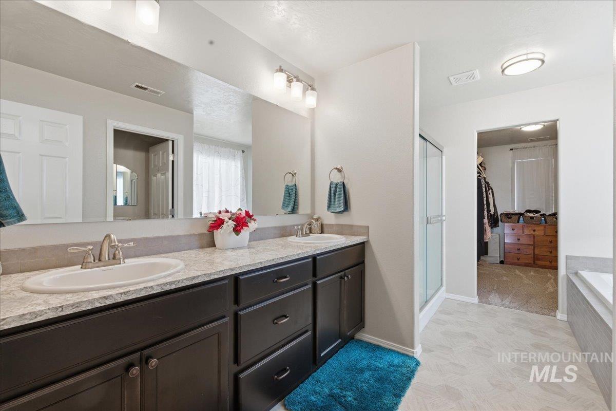 16202 Dietz Way Caldwell, ID 83607 - Photo 14 of 31 Full bath featuring a spacious closet, double vanity, a garden tub, a stall shower, and light colored carpet