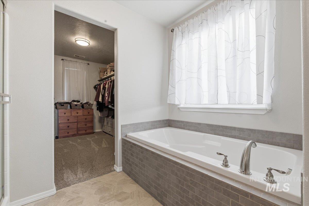 16202 Dietz Way Caldwell, ID 83607 - Photo 15 of 31 Bathroom with a spacious closet, a garden tub, and light carpet