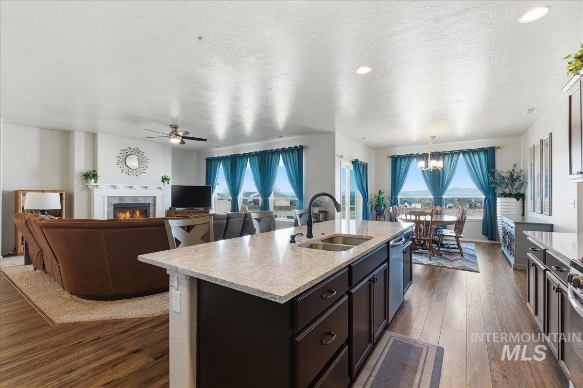 16202 Dietz Way Caldwell, ID 83607 - Photo 29 of 31 Kitchen with light stone counters, dark wood-style floors, a lit fireplace, open floor plan, and a textured ceiling