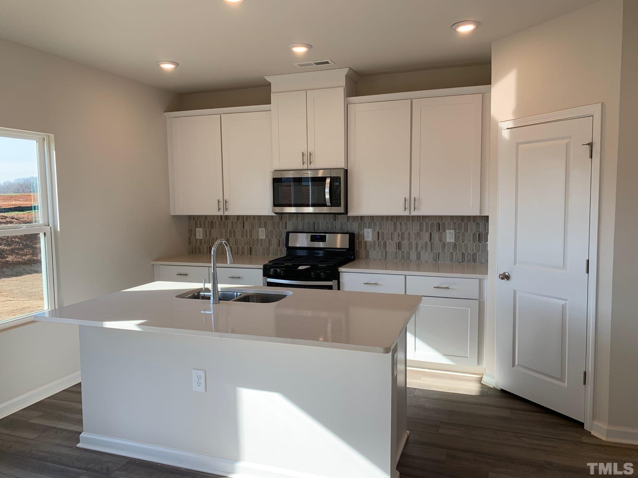 7138 Stratified Court Mebane, NC 27302 - Photo 2 of 6 a kitchen with kitchen island granite countertop a sink and a stove top oven with wooden floor