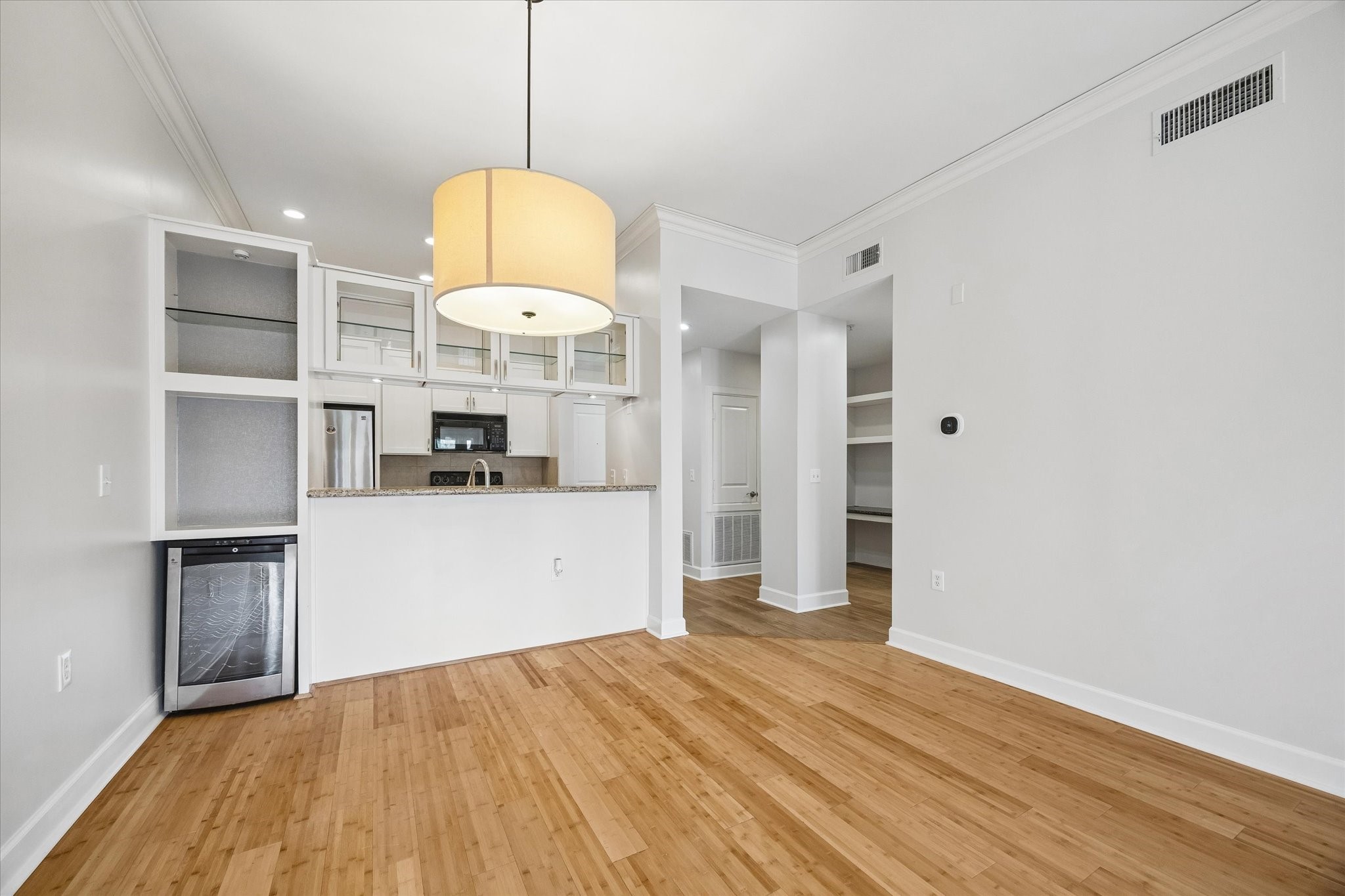 100 Willard Street, Unit 15 Houston, TX 77006 - Photo 7 of 25 Open sightlines connect the living, dining, and kitchen spaces, while glass-front upper cabinetry, crown molding, and warm bamboo floors add a sophisticated touch.