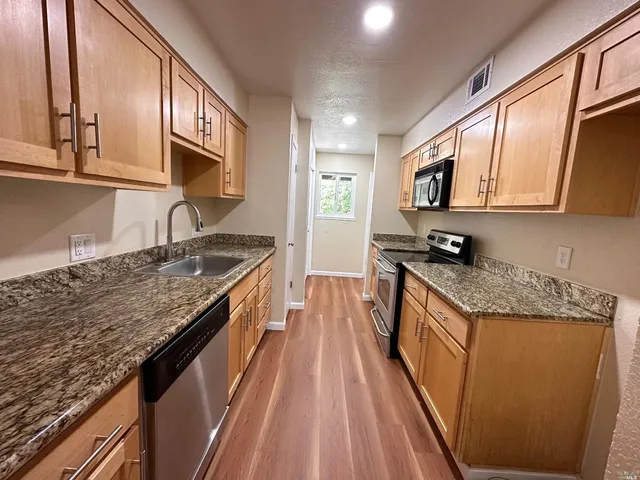 a kitchen with stainless steel appliances granite countertop a stove a sink and a microwave