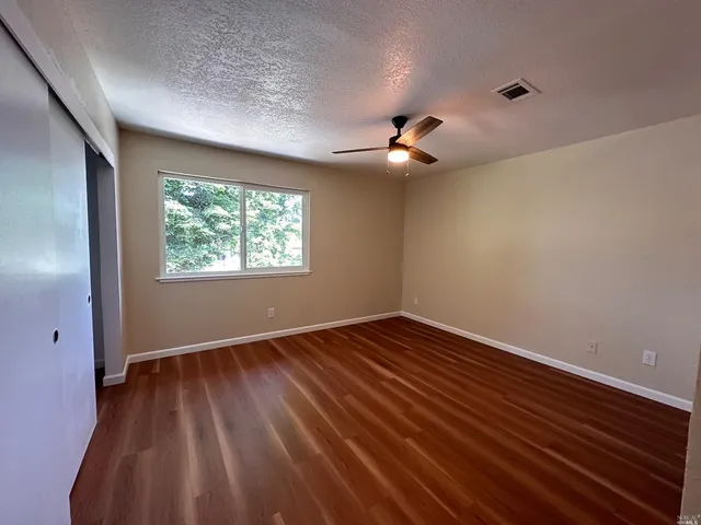 a view of an empty room with wooden floor and a window