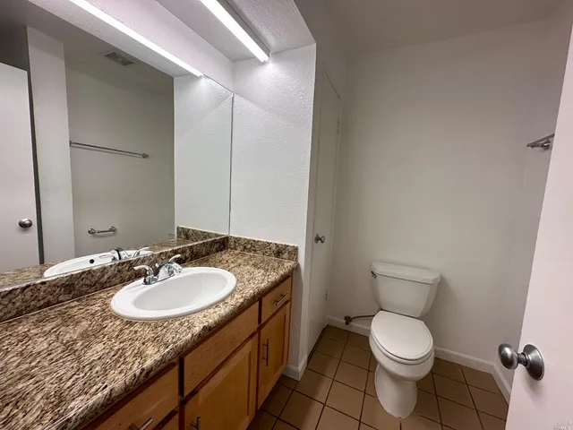 a bathroom with a granite countertop sink a toilet and a mirror