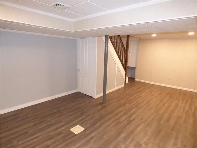 a view of an empty room with wooden floor and stairs