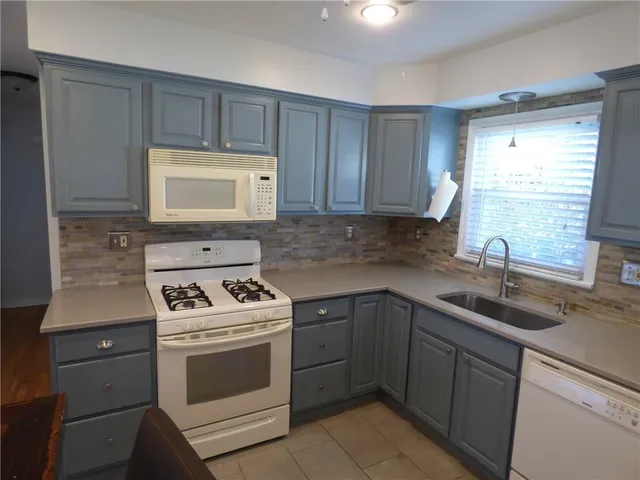 a kitchen with cabinets appliances a sink and a window