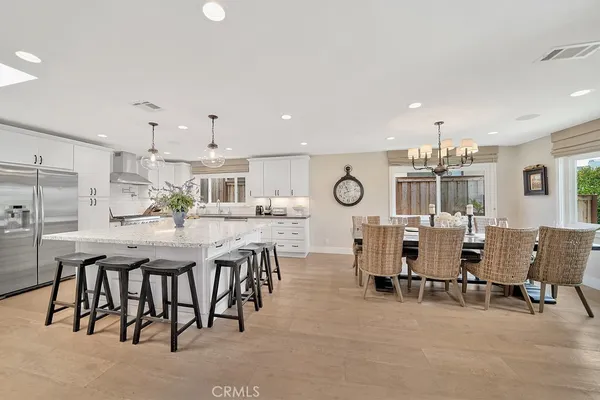 a kitchen with stainless steel appliances kitchen island granite countertop a table chairs and a refrigerator