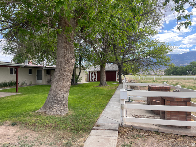 438 East Main Street Elsinore, UT 84724 - Photo 8 of 43 Expansive property featuring a manicured lawn, established shade trees, a white picket fence, and a distant mountain backdrop