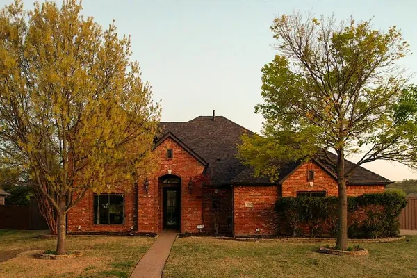 a front view of a house with a yard and large trees