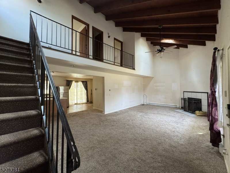 a view of an empty room with wooden floor and a staircase