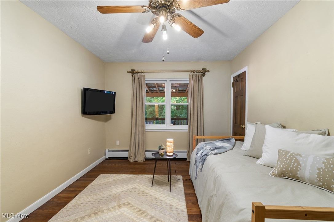 1599 Riverside Drive Akron, OH 44310 - Photo 16 of 37 Bedroom featuring dark wood finished floors, a textured ceiling, a ceiling fan, and baseboard heating