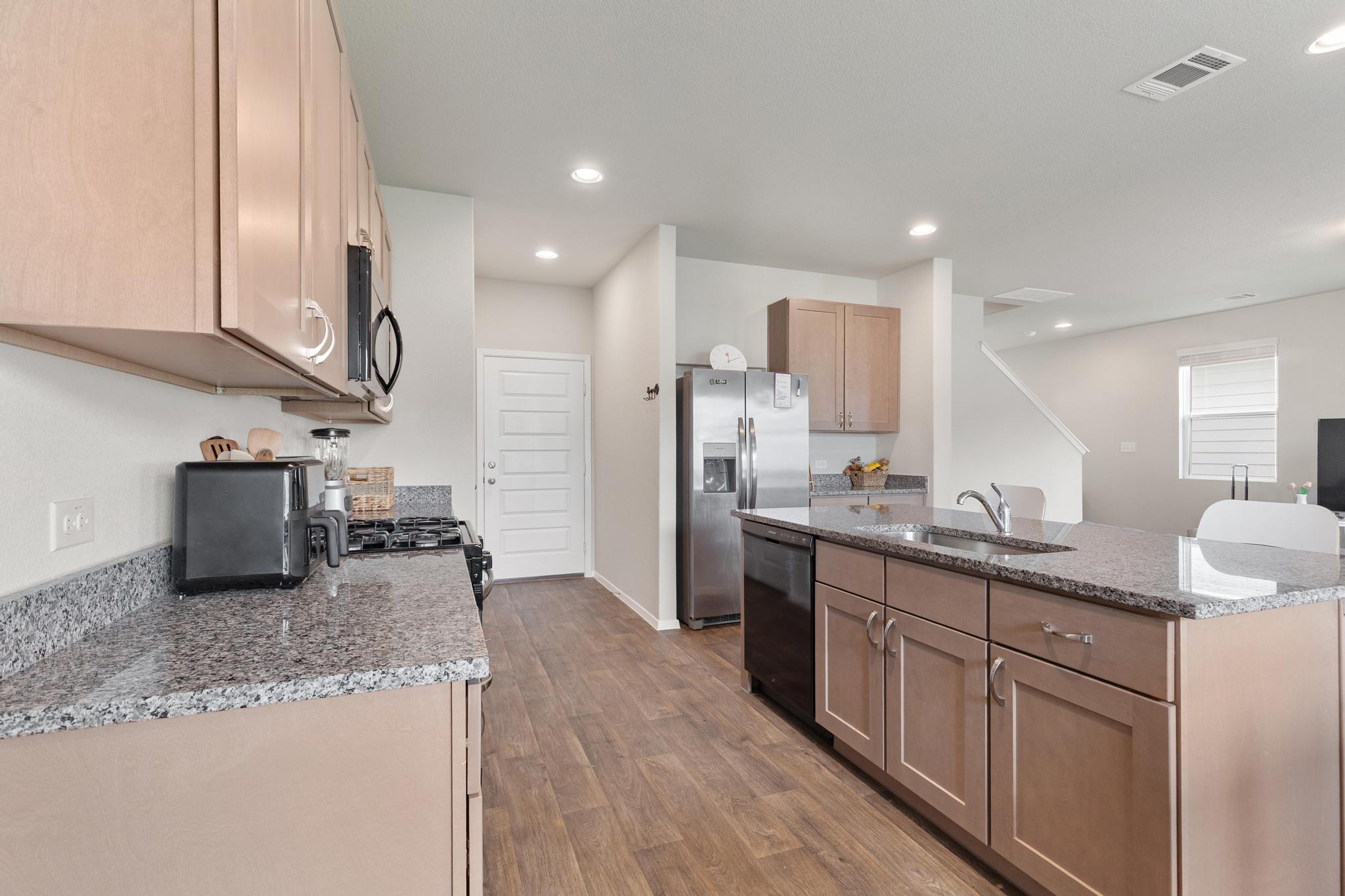 242 Barley Lane Elgin, TX 78621 - Photo 13 of 31 Modern kitchen featuring granite countertops, wood-finish flooring, stainless steel appliances, recessed lighting, and ample cabinetry
