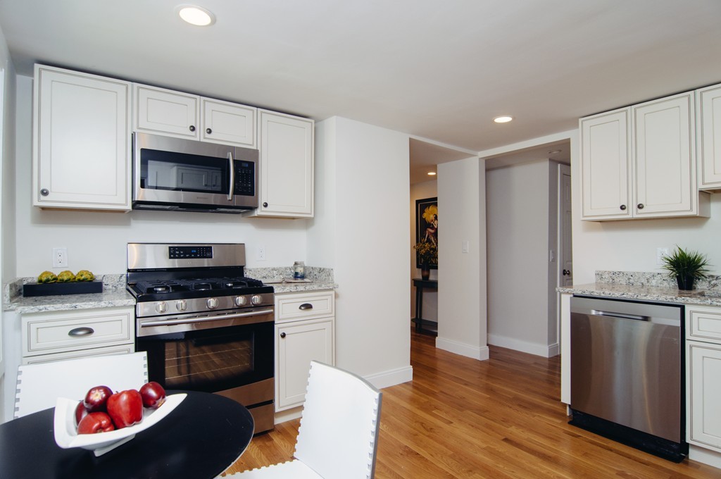 16 Port Norfolk Street, Unit 2 Boston, MA 02122 - Photo 5 of 13 a kitchen with stainless steel appliances granite countertop a stove a microwave and a refrigerator