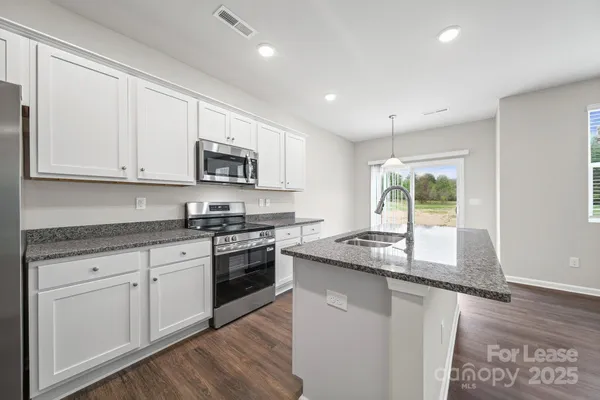 a kitchen with granite countertop a stove top oven sink and cabinets