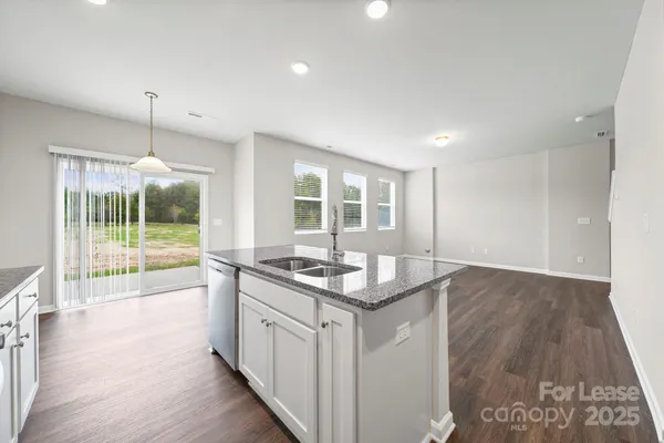 a kitchen with granite countertop a sink and a wooden floor