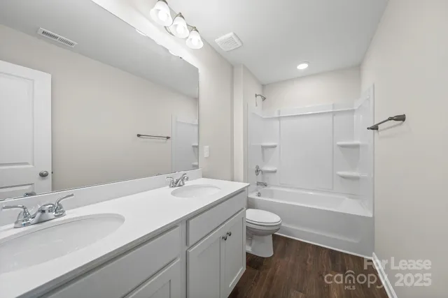 a bathroom with a double vanity sink toilet mirror and shower