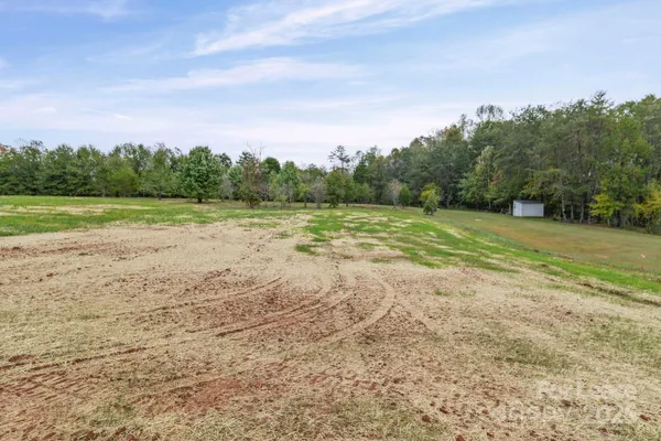 a view of dirt field with trees in background