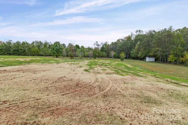 a view of dirt field with trees in background