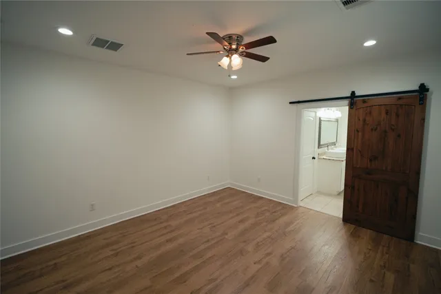 an empty room with wooden floor and a ceiling fan