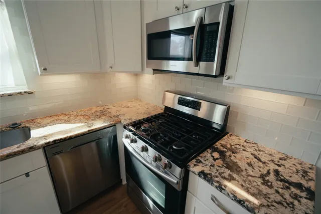 a kitchen with granite countertop a stove and a microwave