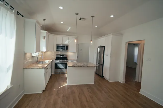 a kitchen with stainless steel appliances granite countertop a refrigerator stove and sink