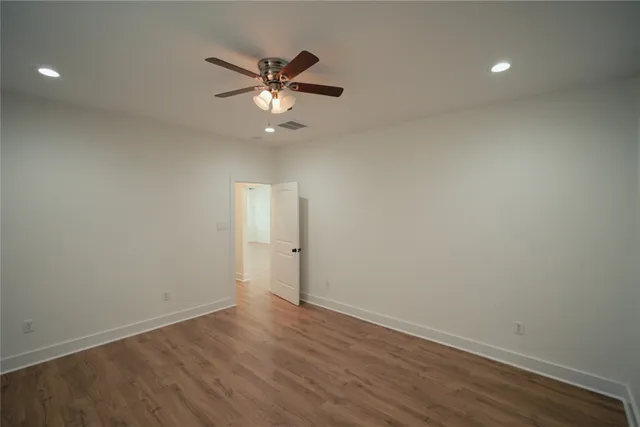 an empty room with wooden floor fan and windows