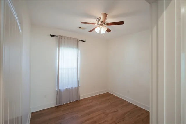 an empty room with wooden floor closet and fan
