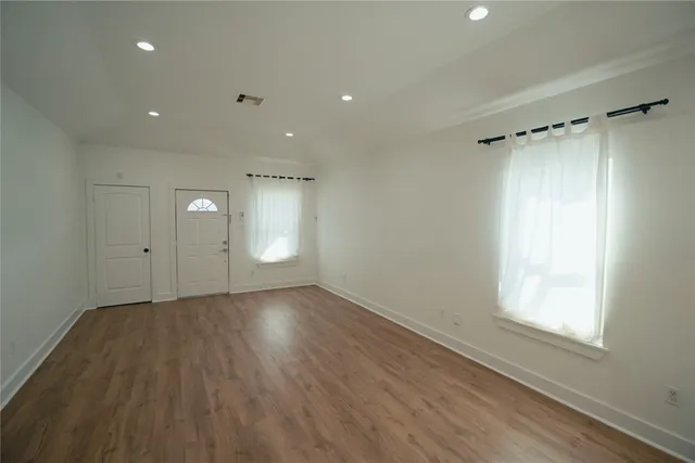 a view of an empty room with a window and wooden floor
