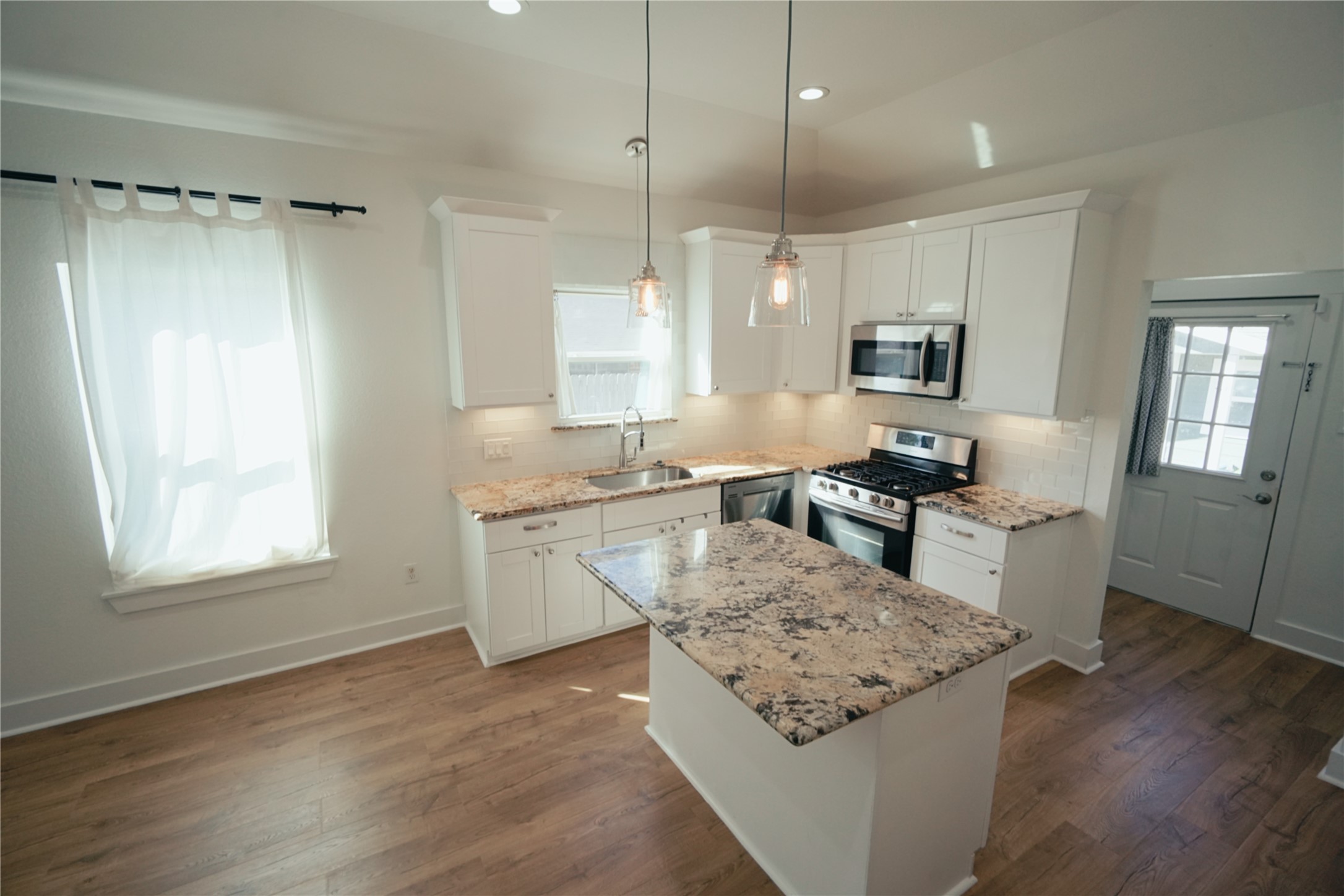 5105 Chapman Street Houston, TX 77009 - Photo 7 of 49 a large kitchen with kitchen island white cabinets and stainless steel appliances