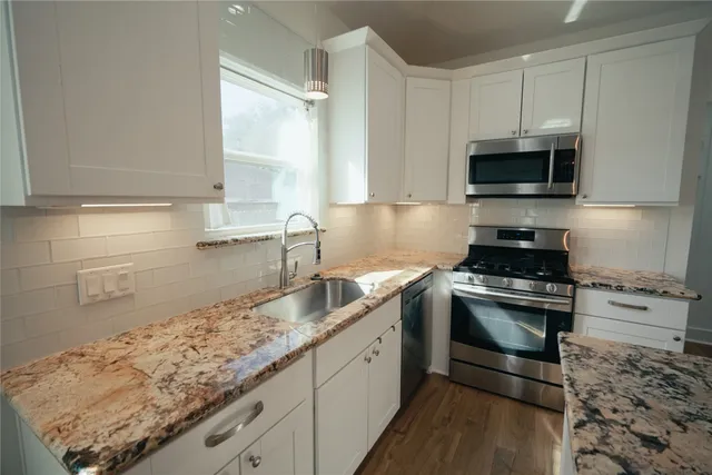 a kitchen with granite countertop a sink stainless steel appliances and cabinets