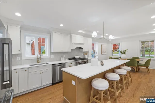 a kitchen with a dining table chairs sink and white cabinets