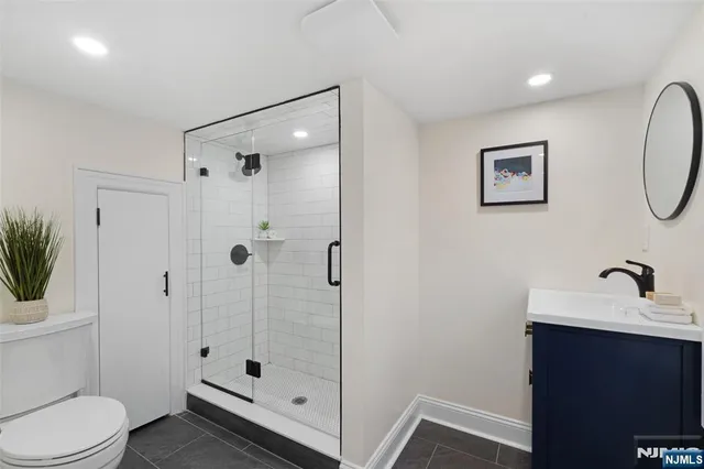 a bathroom with a shower sink vanity mirror and toilet