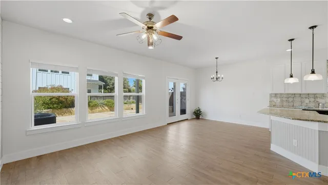 a view of an empty room with a kitchen and a window