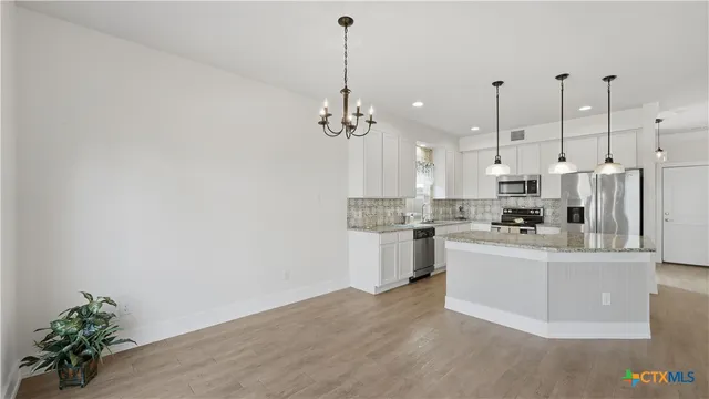 a view of a kitchen with center island and stainless steel appliances