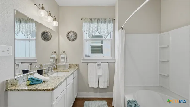 a bathroom with a granite countertop sink a mirror and a shower