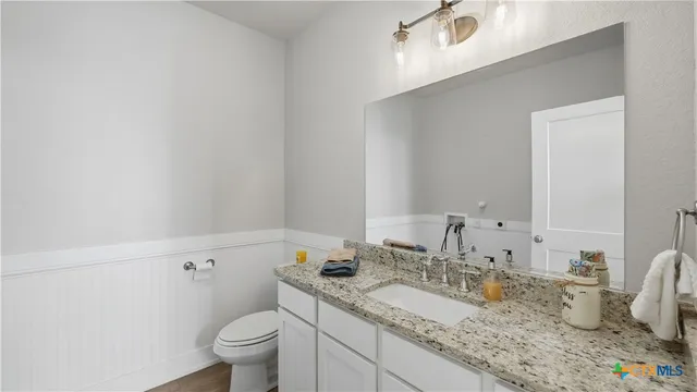 a bathroom with a granite countertop toilet a sink and a mirror