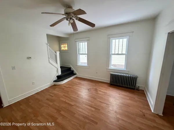 a view of an empty room with a window and wooden floor