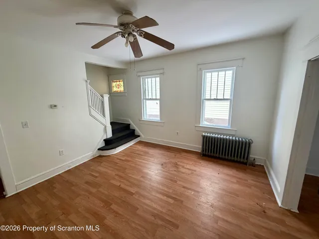 a view of an empty room with a window and wooden floor