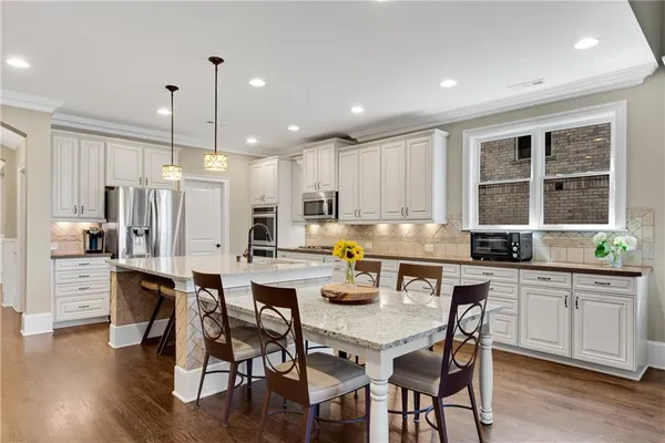 a large kitchen with stainless steel appliances kitchen island a large counter top a stove and a wooden floors