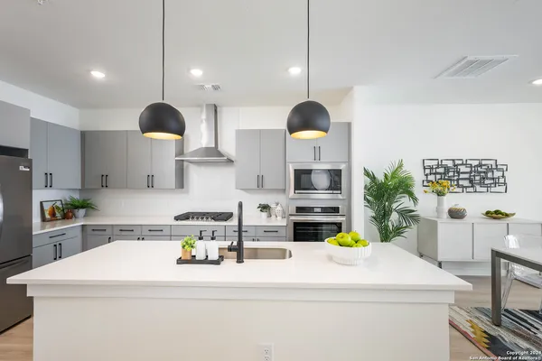 a kitchen with stainless steel appliances a stove a sink a refrigerator and a wooden floor