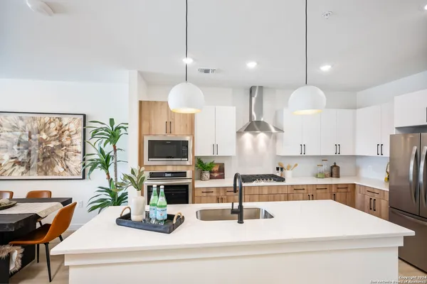 a kitchen with stainless steel appliances kitchen island granite countertop a sink a stove and a wooden floors