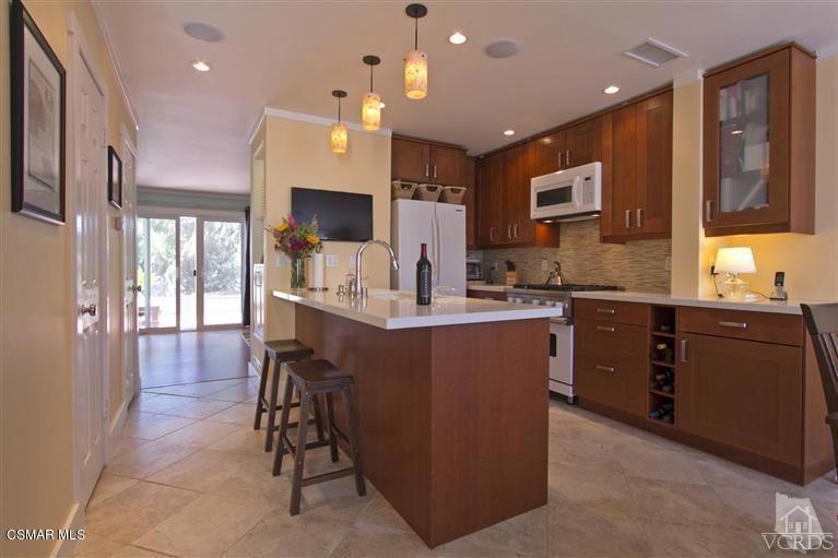 a kitchen with kitchen island granite countertop a stove a sink a refrigerator and a dining table