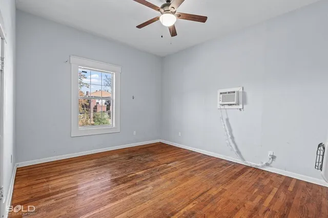 a view of an empty room with window and wooden floor
