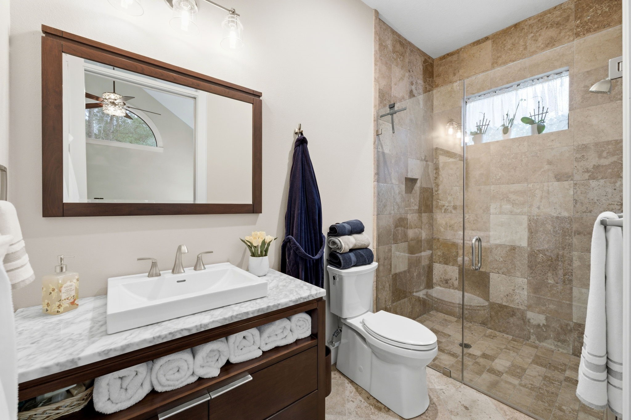 280 Sundog Road Huntsville, TX 77340 - Photo 29 of 50 Guest bathroom featuring a walk-in travertine shower and a vanity with marble countertop and storage.