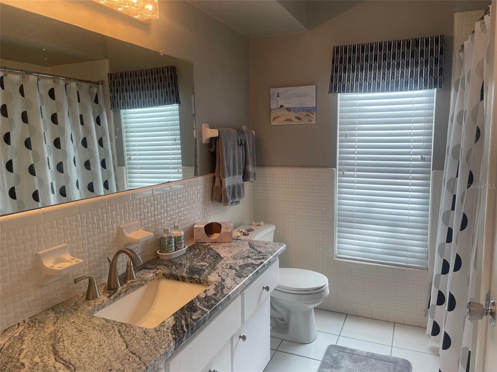 2019 High Ridge Drive Clearwater, FL 33763 - Photo 10 of 30 a bathroom with a granite countertop sink toilet a mirror and shower