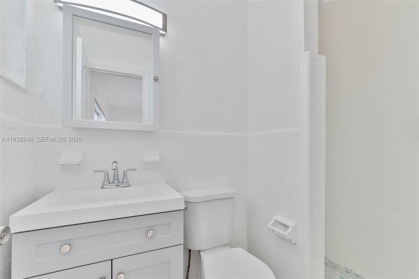 6921 Rue Vendome, Unit 10 Miami Beach, FL 33141 - Photo 11 of 27 a bathroom with a toilet sink and mirror