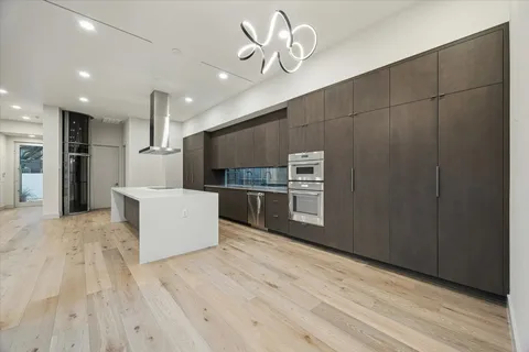 a large kitchen with stainless steel appliances a large counter top a stove and a refrigerator