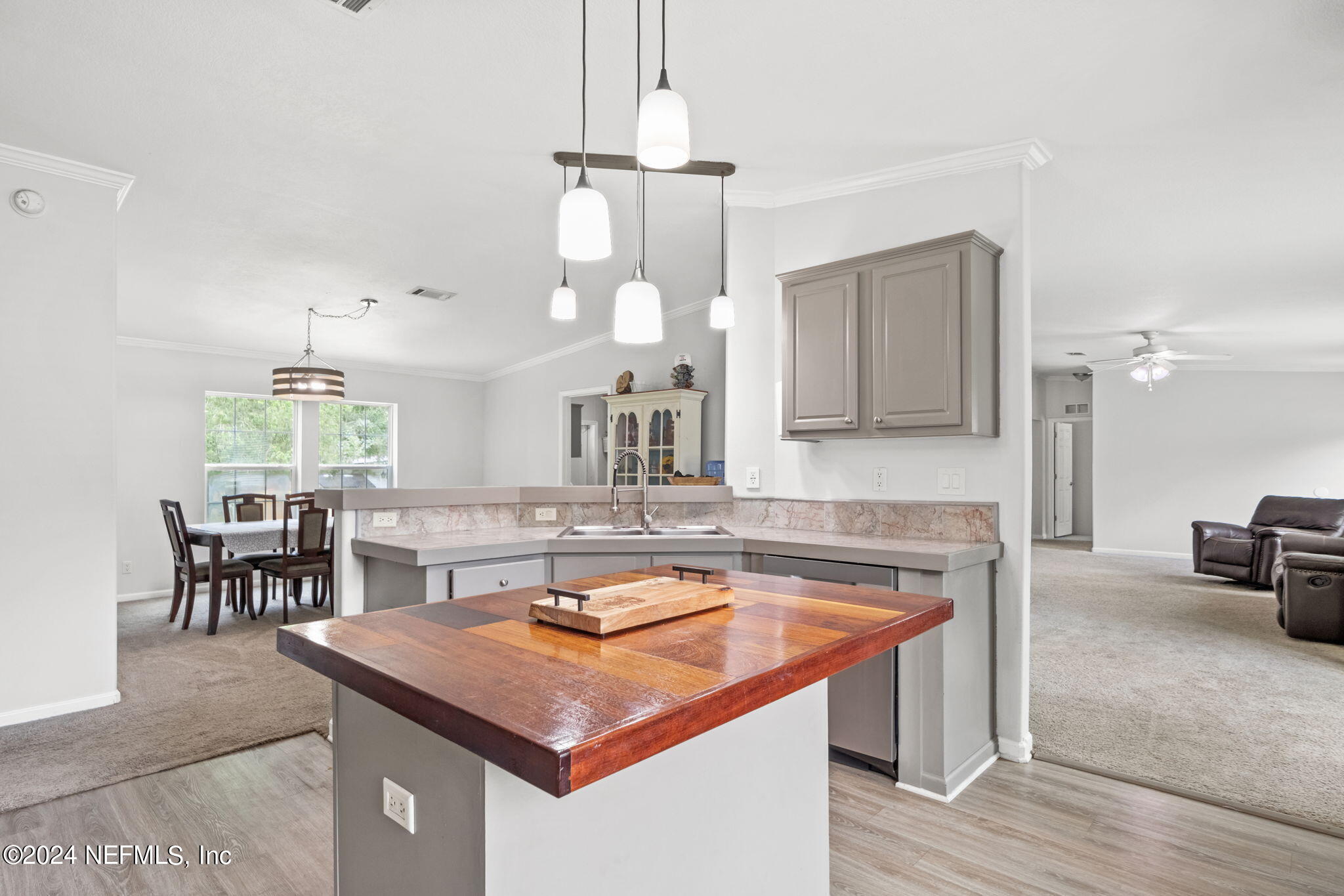 54037 Parks Road Callahan, FL 32011 - Photo 9 of 26 a kitchen with a stove a sink a kitchen island with chairs and wooden floor