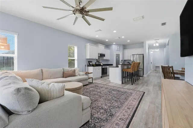 a kitchen with stainless steel appliances granite countertop a stove top oven a sink a refrigerator with white cabinets and wooden floor